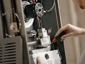 Furnace repair technician inspecting internal components and wiring in Detroit, MI
