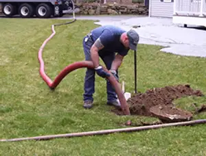 Septic pumping technician servicing a residential septic tank with a vacuum hose in Detroit, MI