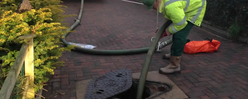 Septic tank cleaning technician servicing a septic tank with a vacuum hose in Detroit, MI