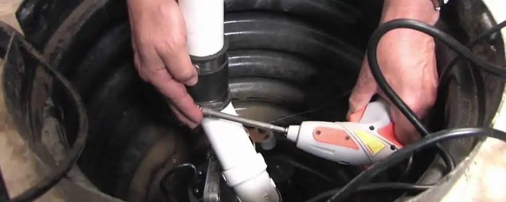 Sump pump installation technician connecting PVC discharge piping in Detroit, MI